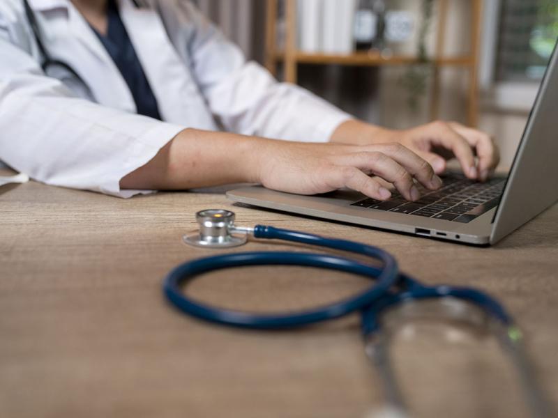 Doctor types on a laptop