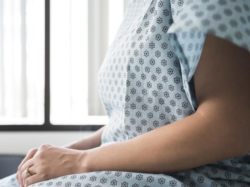 Midsection of patient in hospital gown waiting in exam room