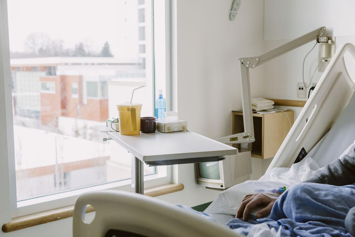 Hand of male sitting in hospital bed looking out the window