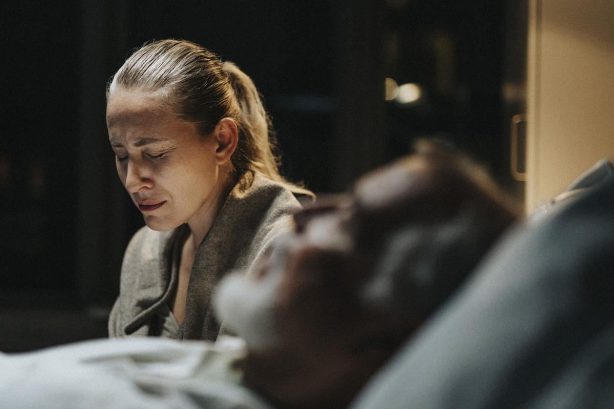 Sad woman crying near ill patient in hospital ward
