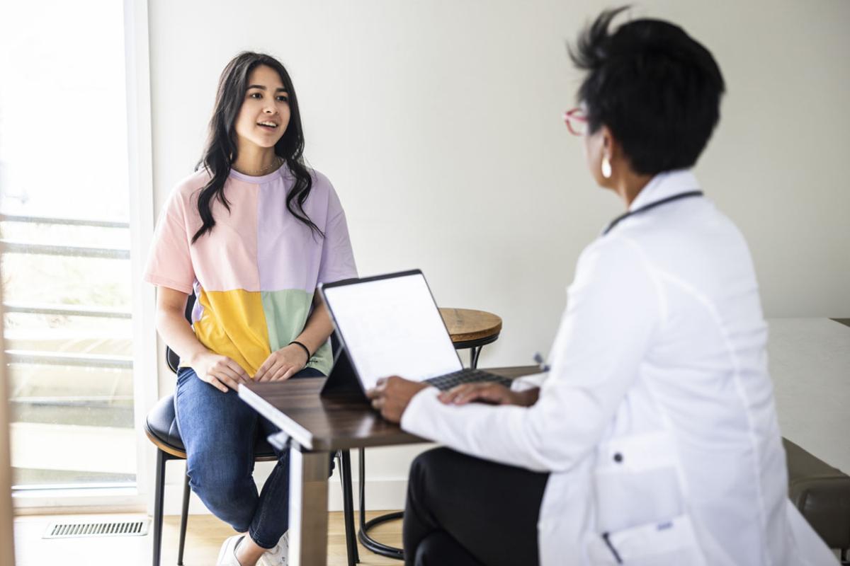 Doctor consulting with teenage patient in exam room