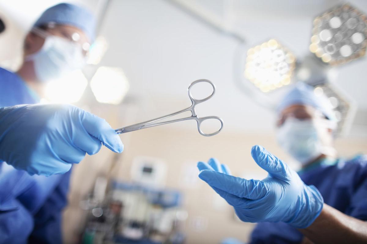 Surgeon passing medical equipment tool in surgery operating room