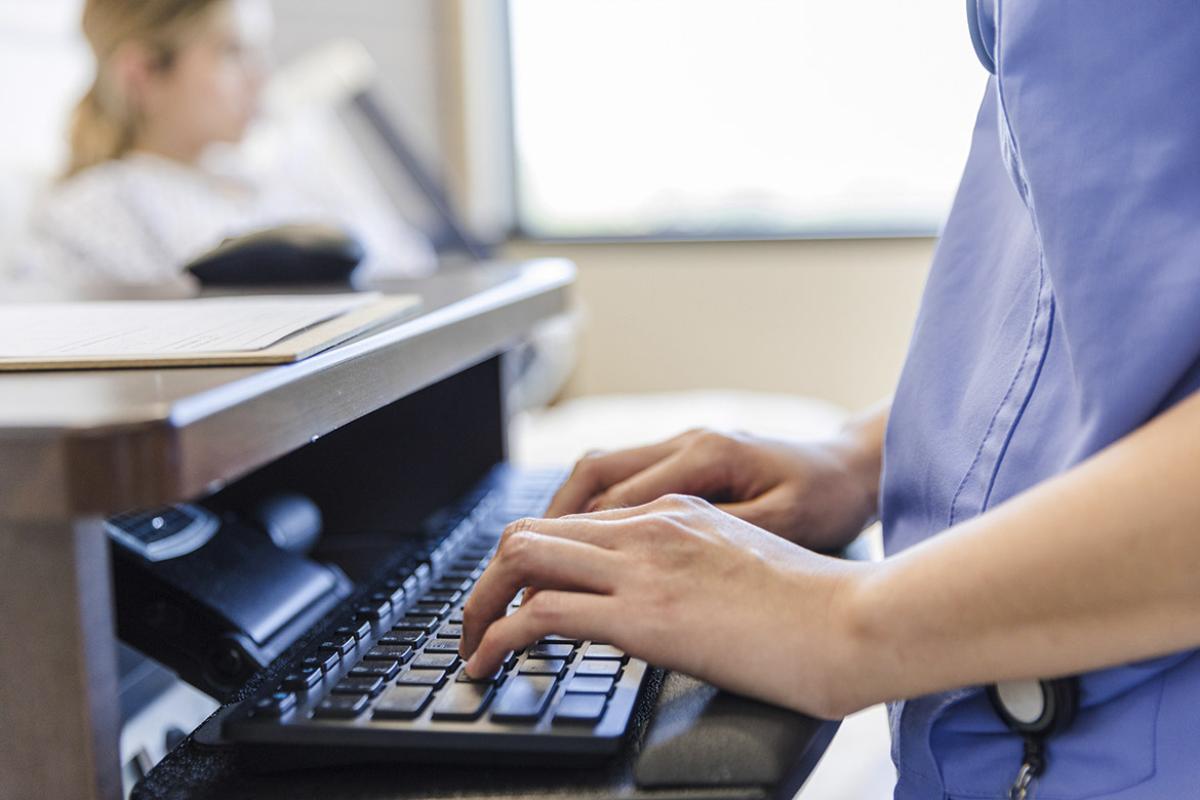 Health care worker typing on a computer keyboard